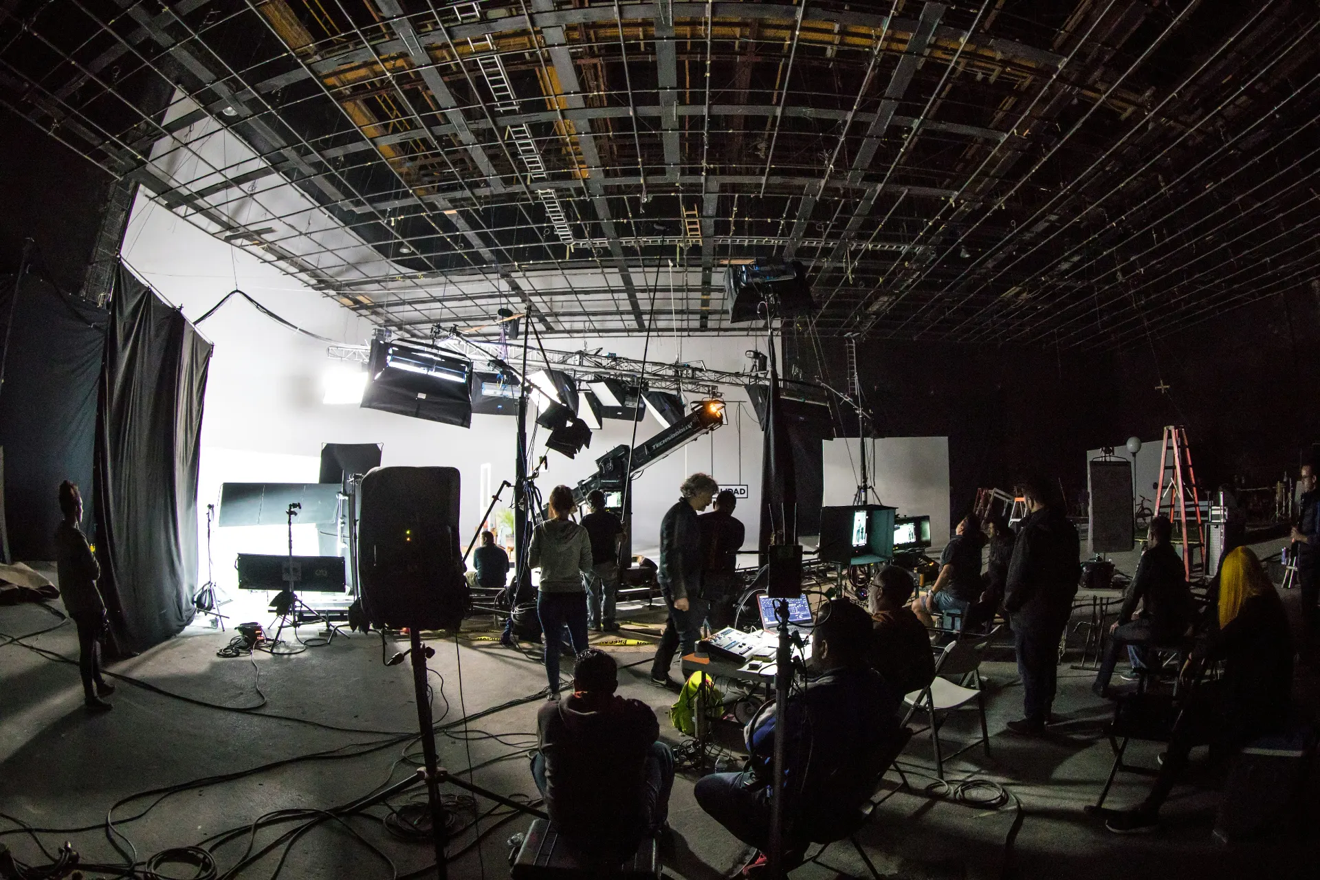 Wide shot of a full film crew working a busy soundstage with lighting rigs and monitors